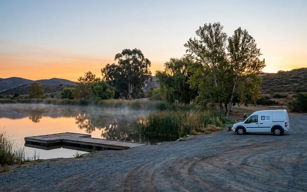 Seven Lakes Locks van parked beside a misty lake and wooden fishing dock at sunrise